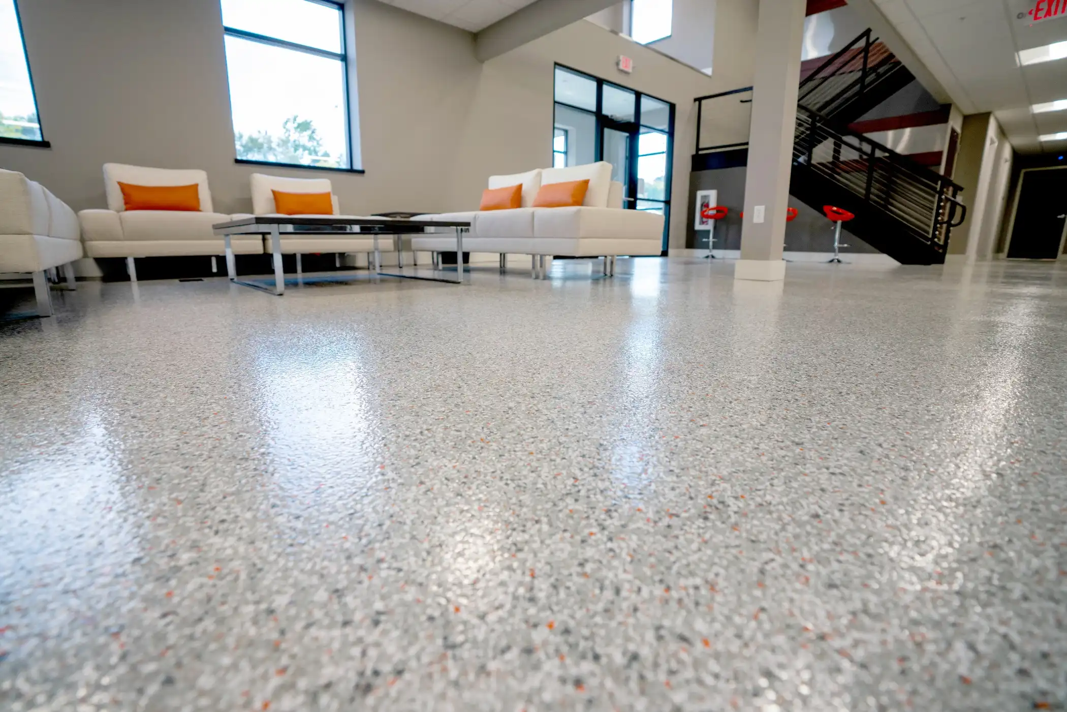 Commercial lobby with a light grey flake polyurea floor, lounge seating and glass entry doors