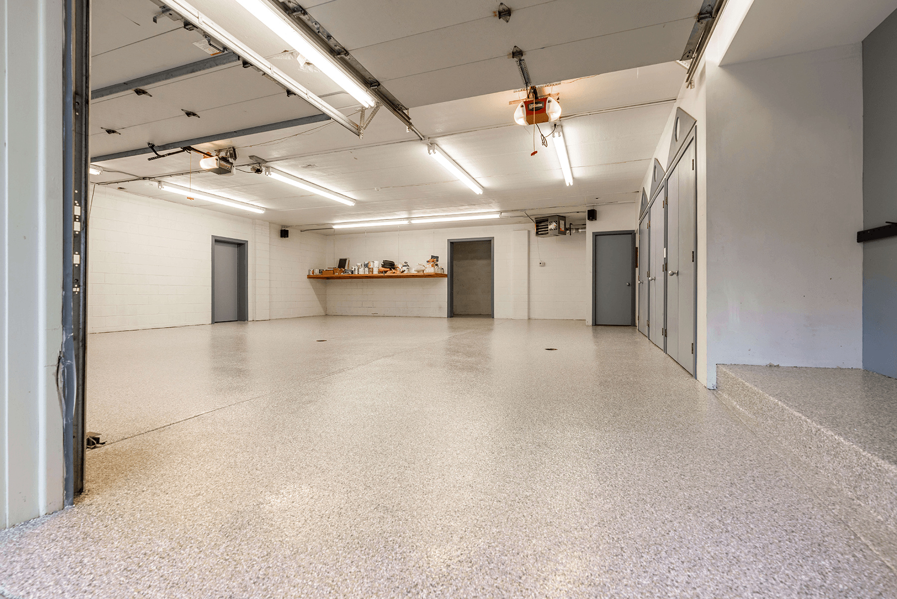 Wide multi-bay garage with a tan flake polyurea floor running wall to wall