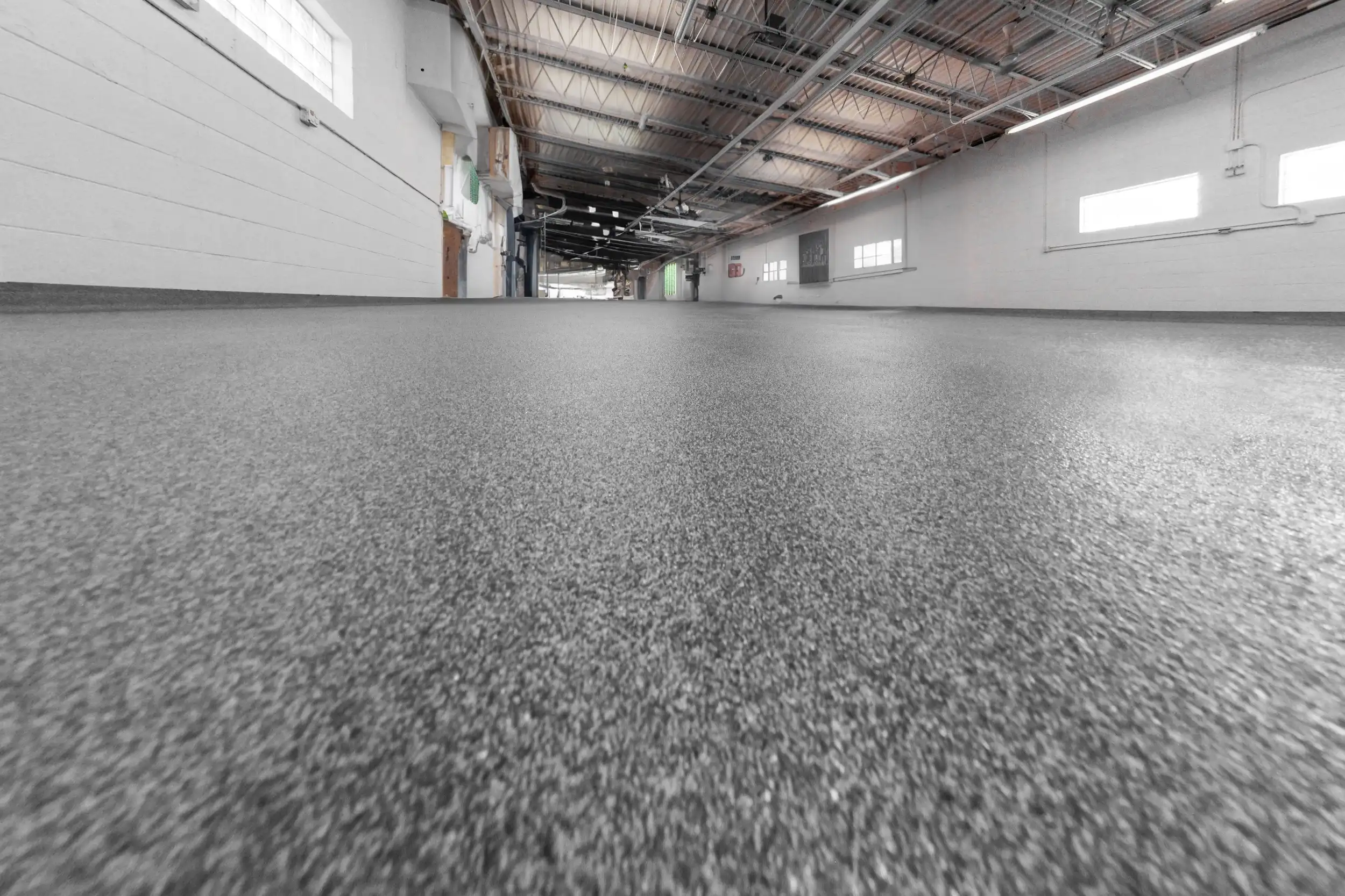 Long commercial corridor with a grey quartz-broadcast polyurea floor